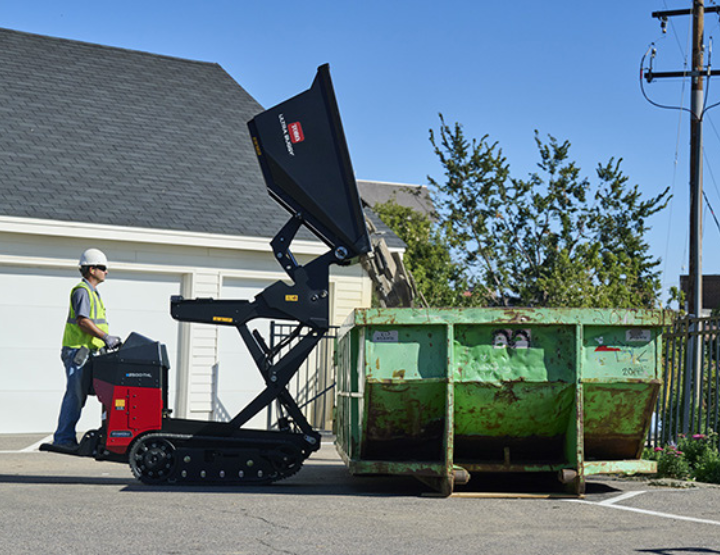 Man extending Toro Electric High Life Ultra Buggy e2500-THL to dump debris into a dumpster