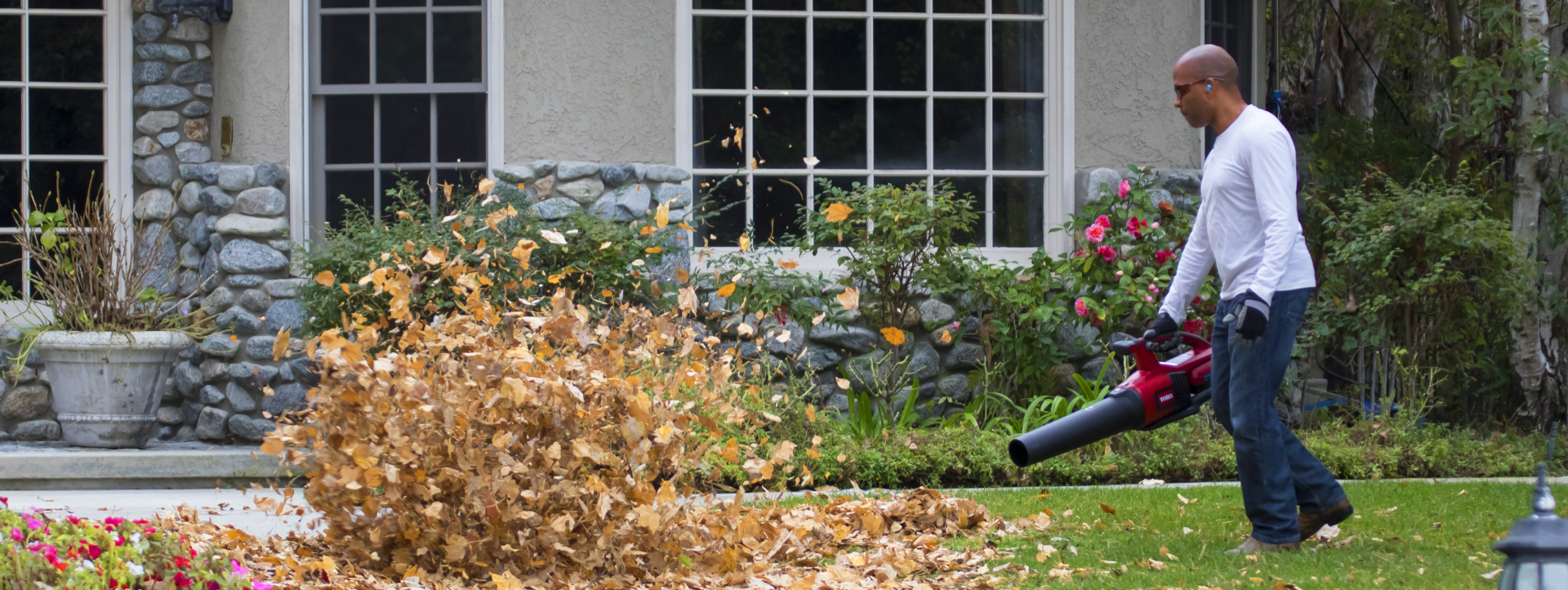Man blowing leaves in front of house with a Toro blower