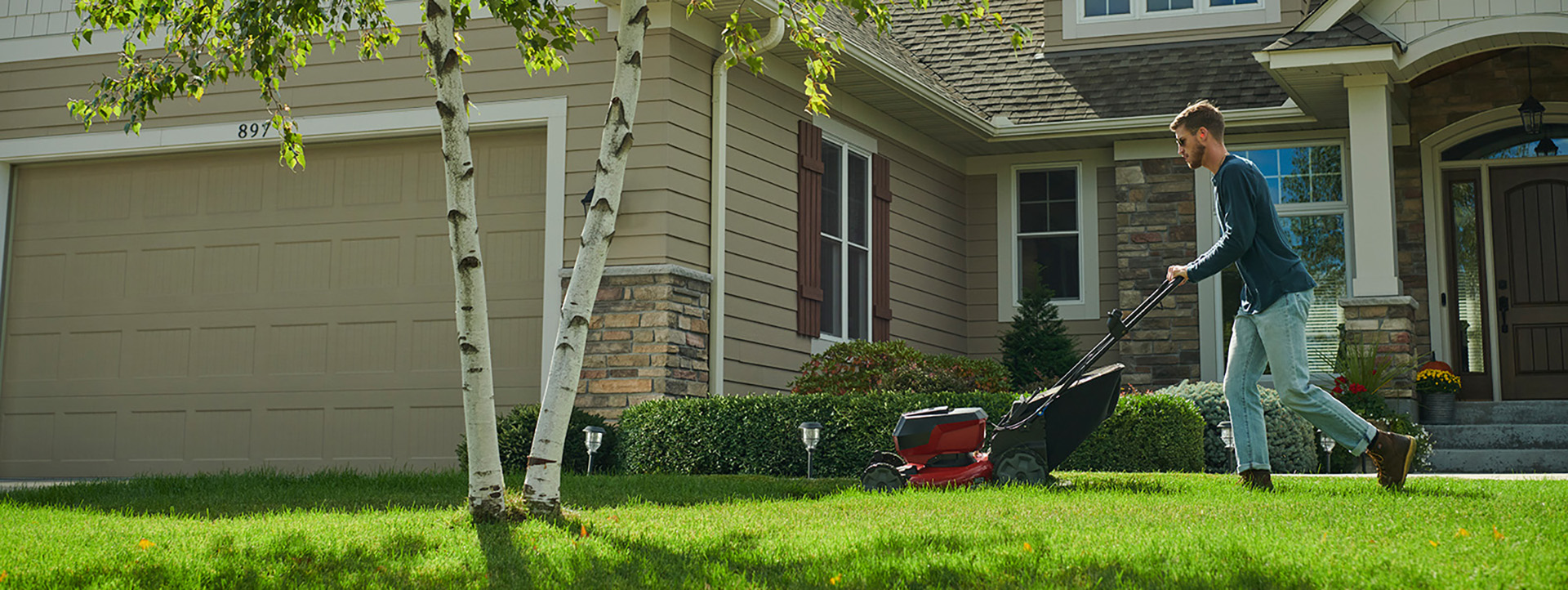 Man mowing the front yard of house with a Toro mower